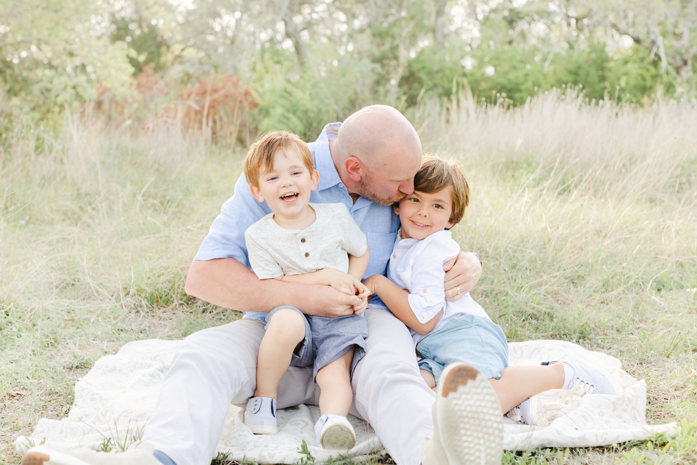 Dad cuddling with two sons during family photoshoot near Cedar Park TX. Photo by Sana Ahmed Photography.