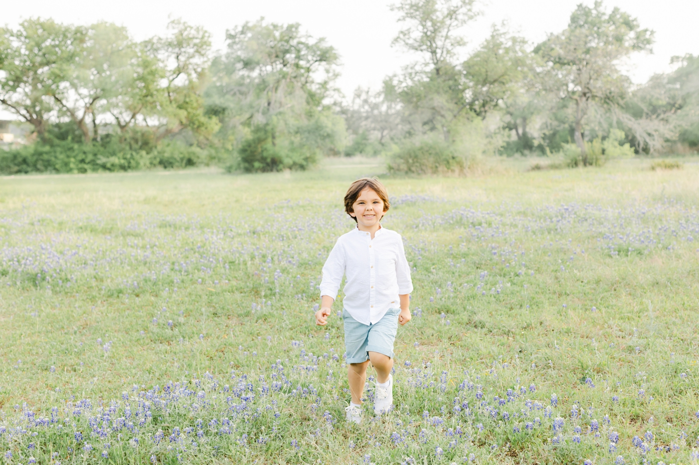 Child playing in field of wildflowers near Cedar Park TX. Photo by Sana Ahmed Photography.