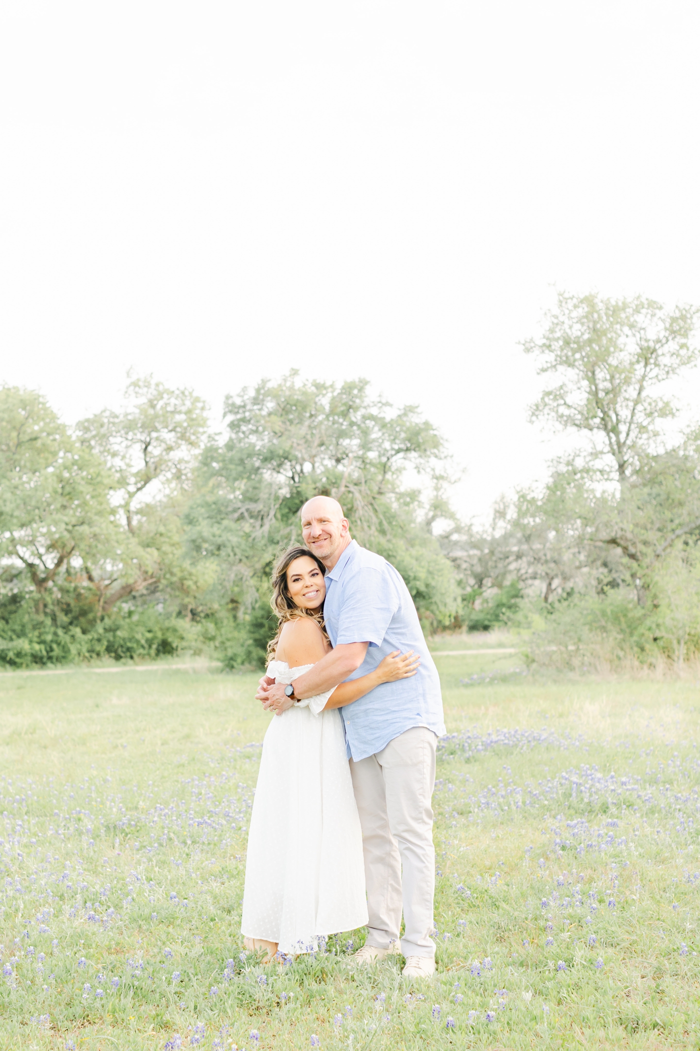 Mom and Dad smiling together in field of wildflowers in Cedar Park, TX. Photo by Sana Ahmed Photography.