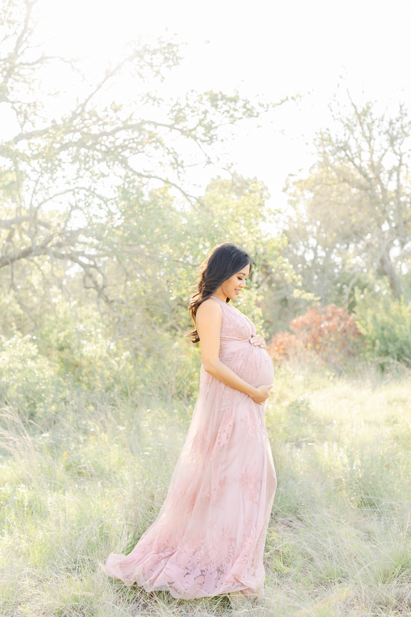 Image of pregnant Mom looking at baby bump during sunny photoshoot with Sana Ahmed Photography.
