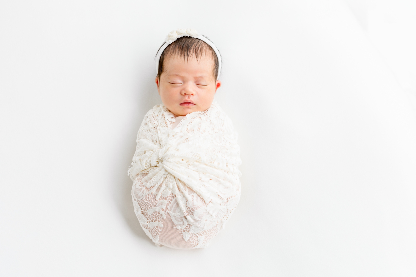 Sleeping baby girl with lace wrap during studio newborn session. Photo by Sana Ahmed Photography.