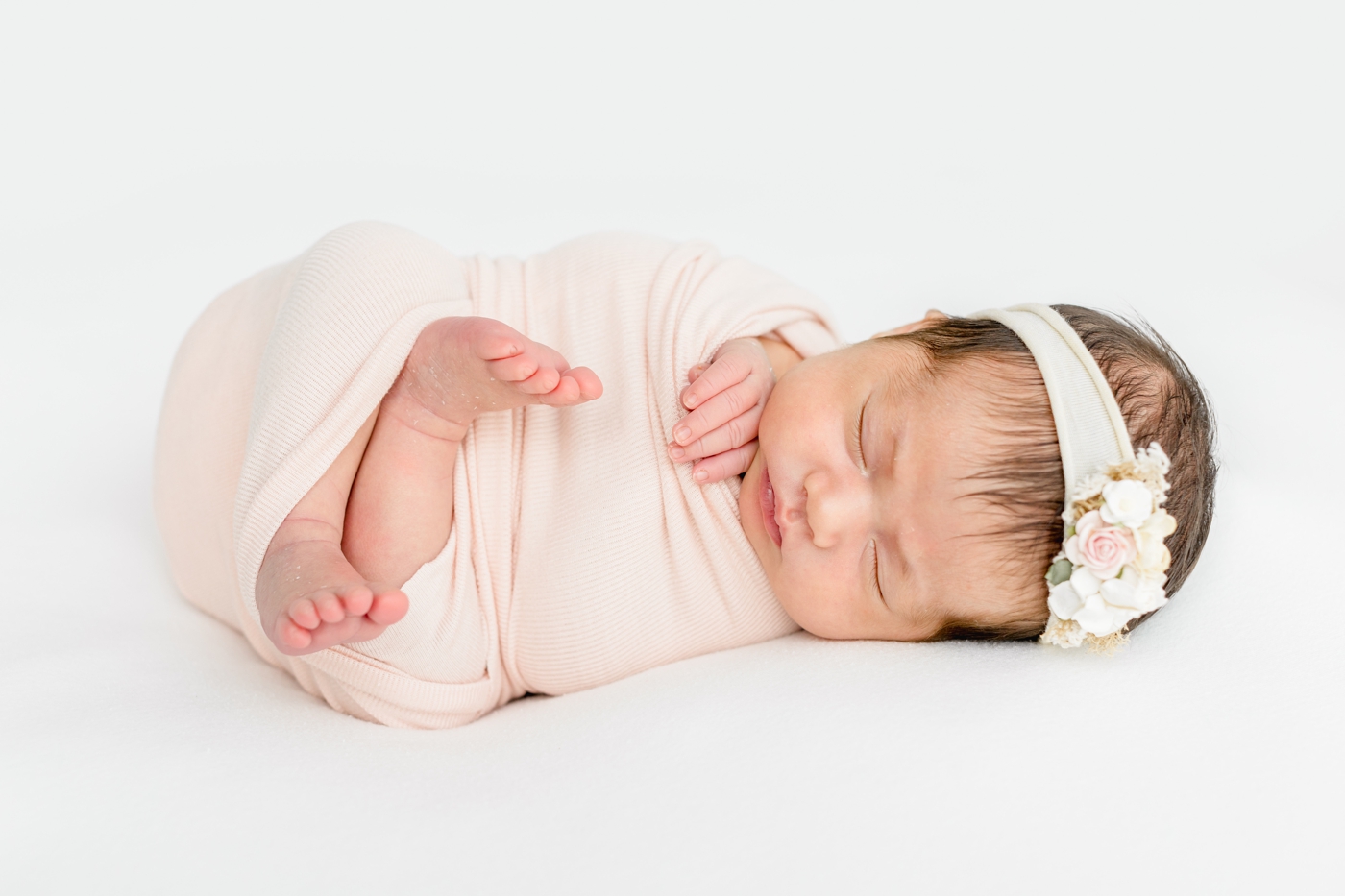 Sleeping baby in pink swaddle during newborn session in Austin, TX studio. Photo by Sana Ahmed Photography.