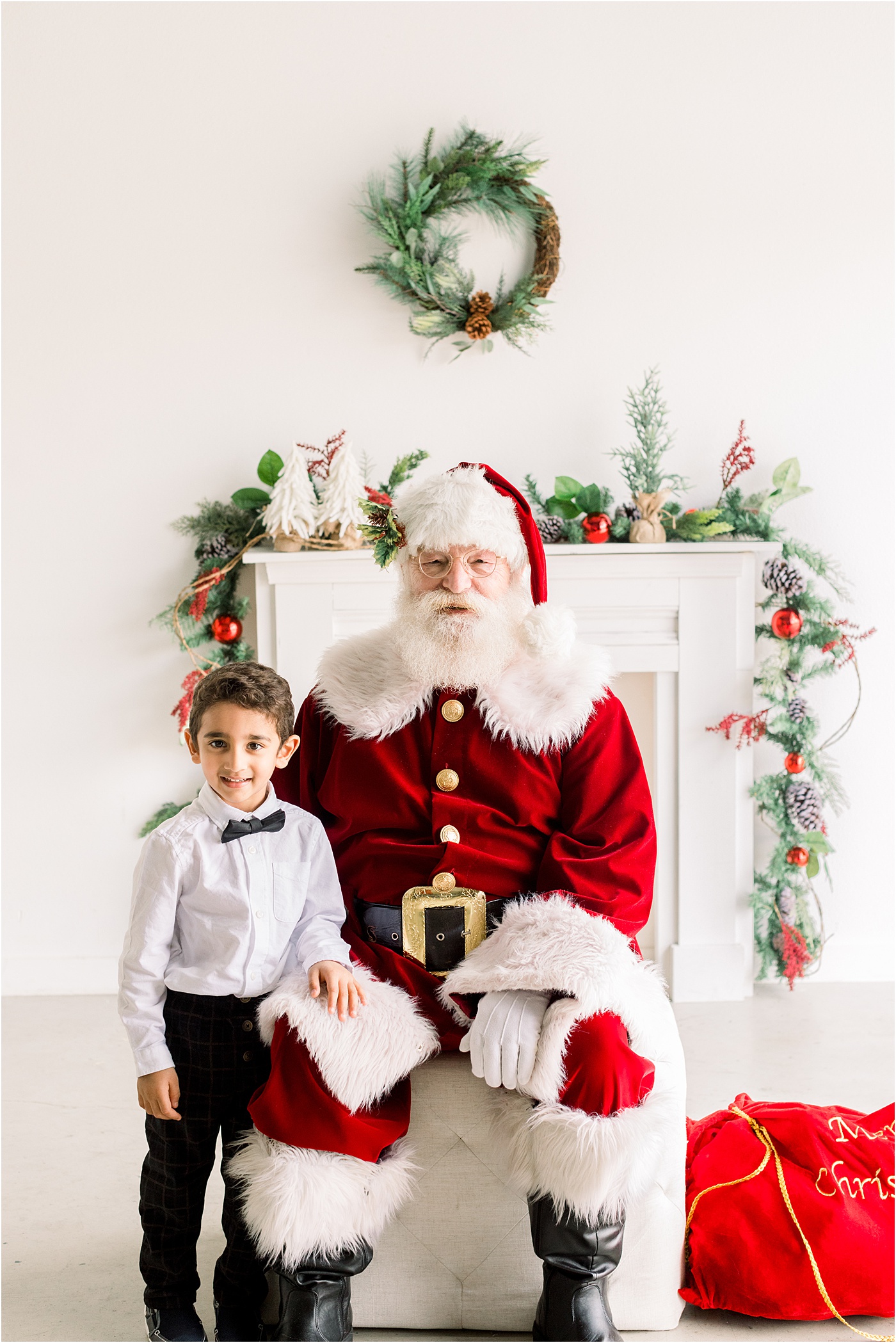 Little boy smiling with Santa during a pictures with Santa event in Austin, TX by Sana Ahmed Photography.