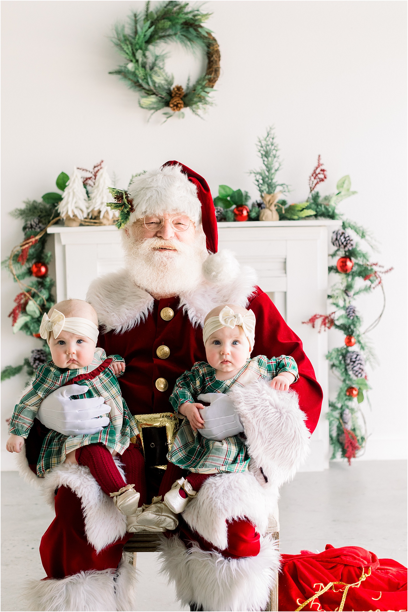 Santa holding adorable twin girls during Christmas photo session with Austin family photographer, Sana Ahmed Photography.