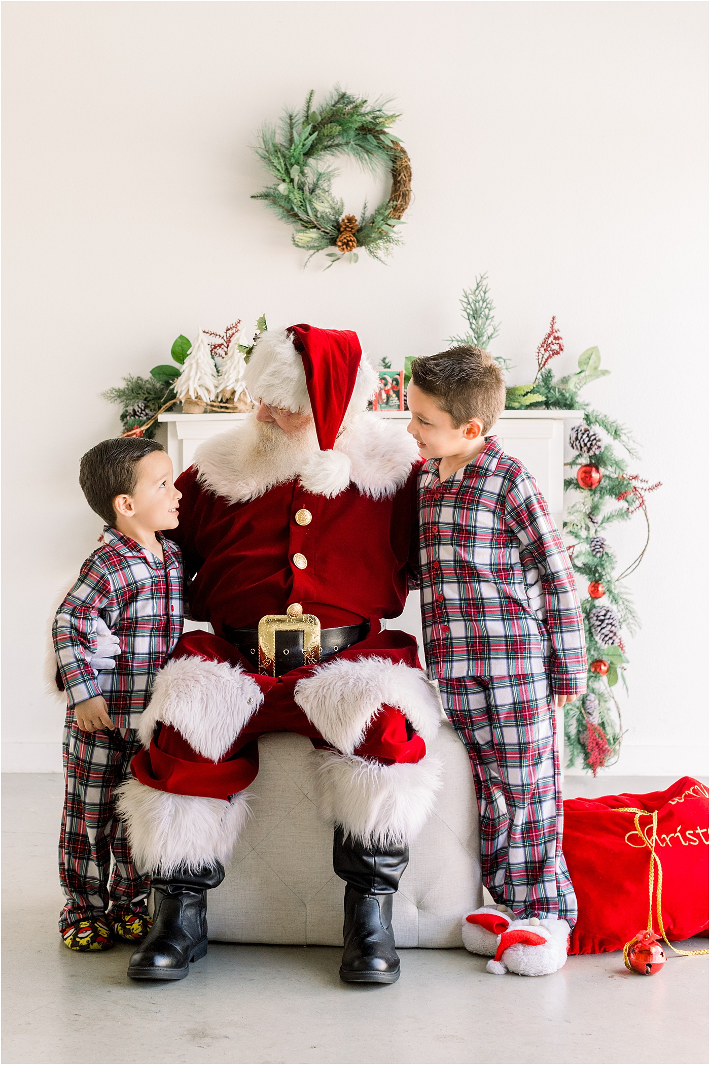 Kids wearing plaid pajamas during photos with Santa in Austin, TX by Sana Ahmed Photography.