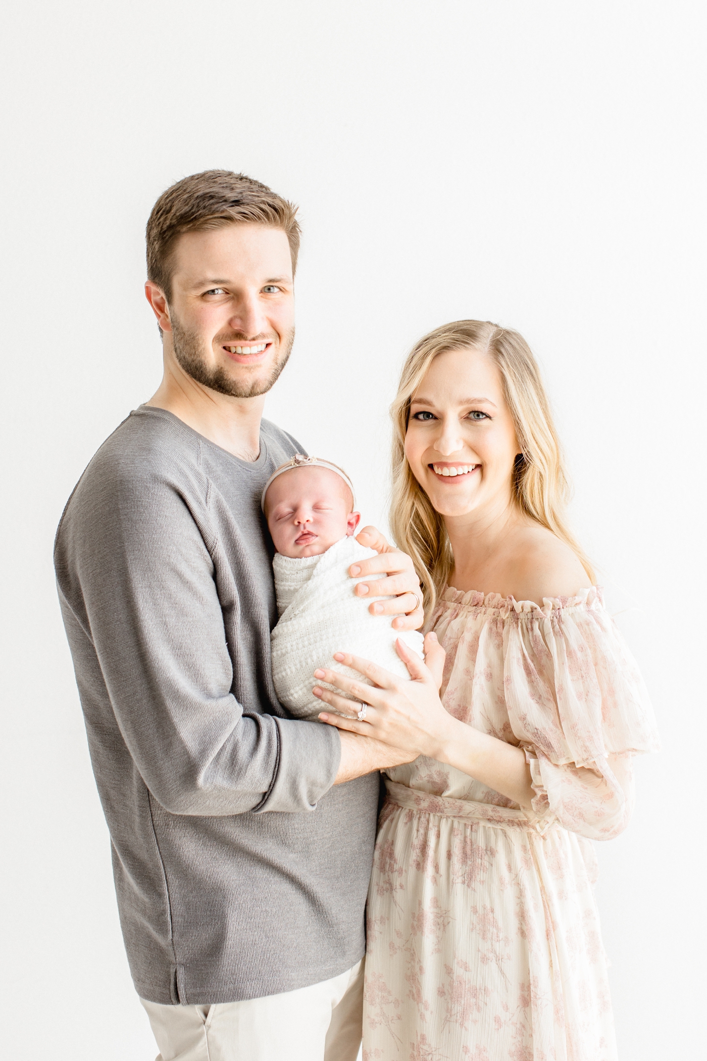 Traditional portrait of family smiling at camera during studio newborn session. Photo by Sana Ahmed Photography.