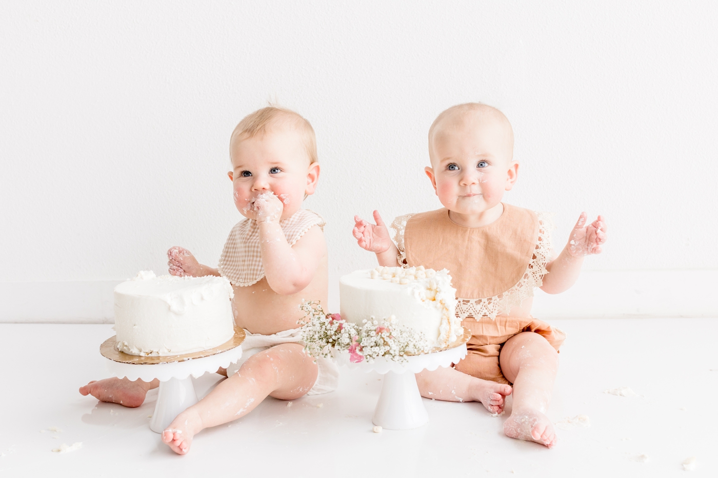 Twins smiling at camera during first birthday cake smash session. Photo by Austin family photographer, Sana Ahmed Photography.