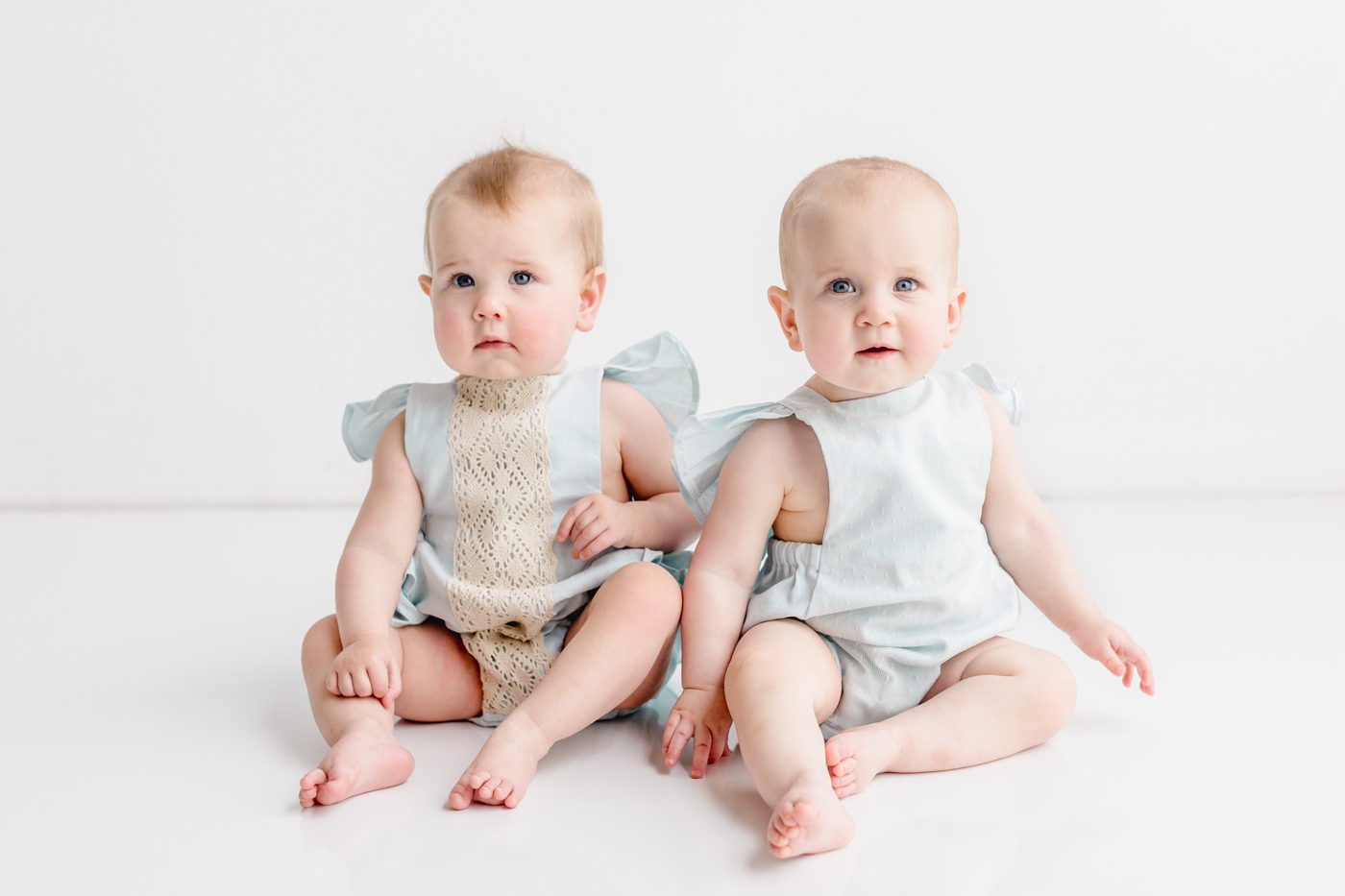Twin girls in blue rompers during milestone portrait session with Sana Ahmed Photography.