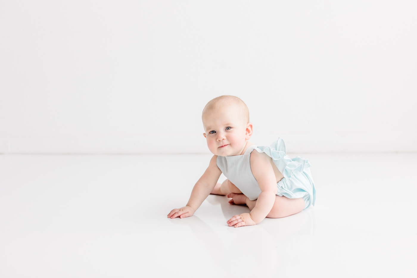 Little girl smiling and beginning to crawl during milestone session with Austin baby photographer, Sana Ahmed Photography.