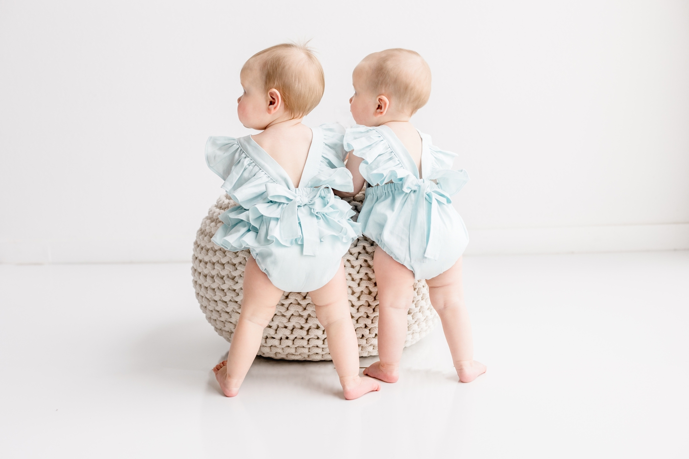 Adorable blue rompers on twin girls with bow and ruffle in the back. Photo from first birthday photo session with Sana Ahmed Photography.