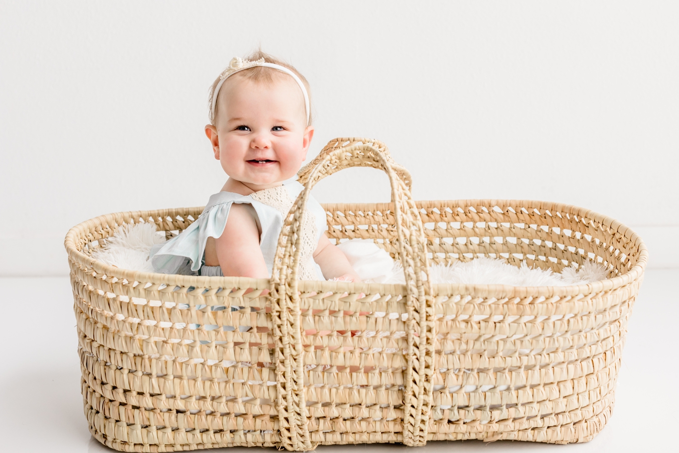 Baby smiling while sitting in moses basket during milestone session with Austin photographer, Sana Ahmed.