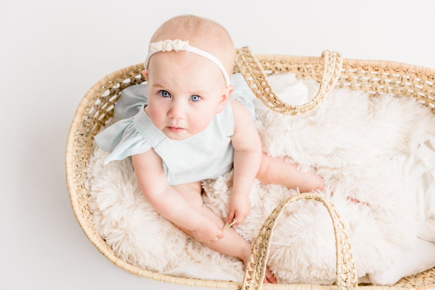 Closeup of baby girl as she sits in moses basket during milestone session in Austin, TX. Photo by Sana Ahmed Photography.