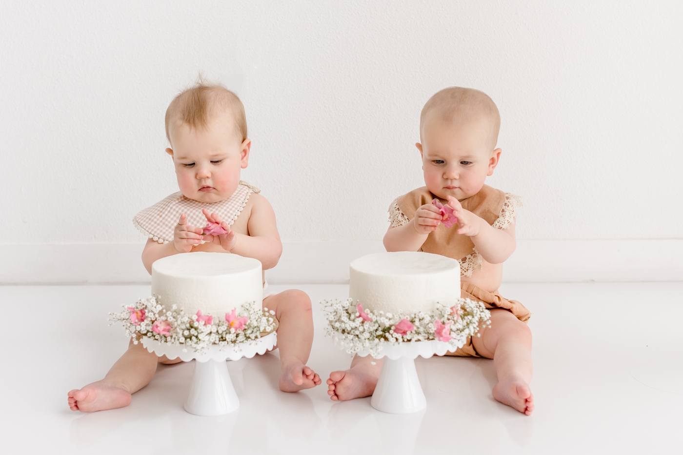 Twin cake smash with white cakes and florals in Austin, TX studio with Sana Ahmed Photography.