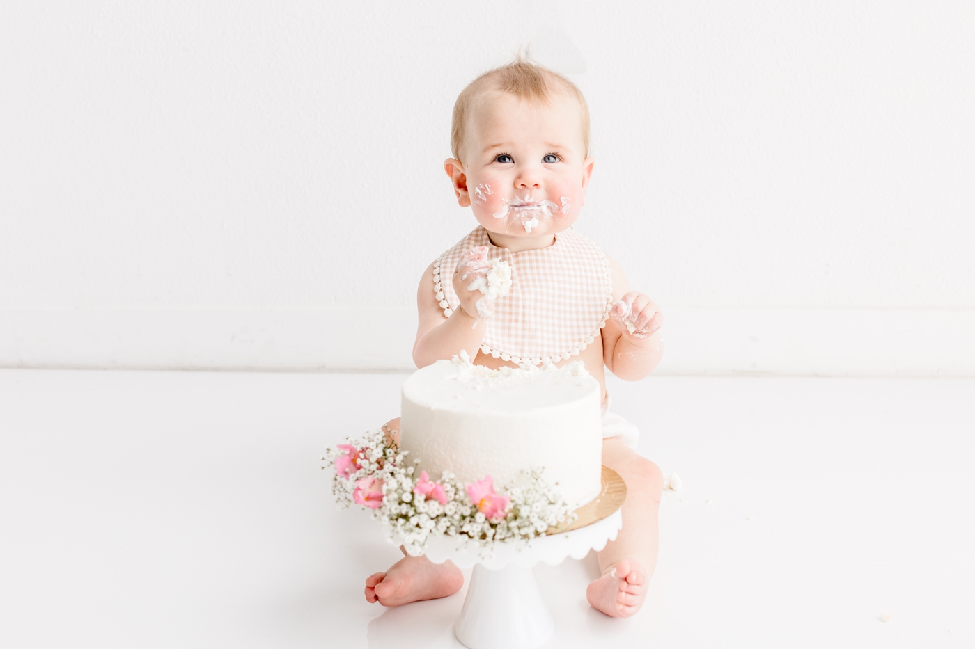 Smiling baby with frosting on cheeks during first birthday photo session with Austin photographer, Sana Ahmed Photography.