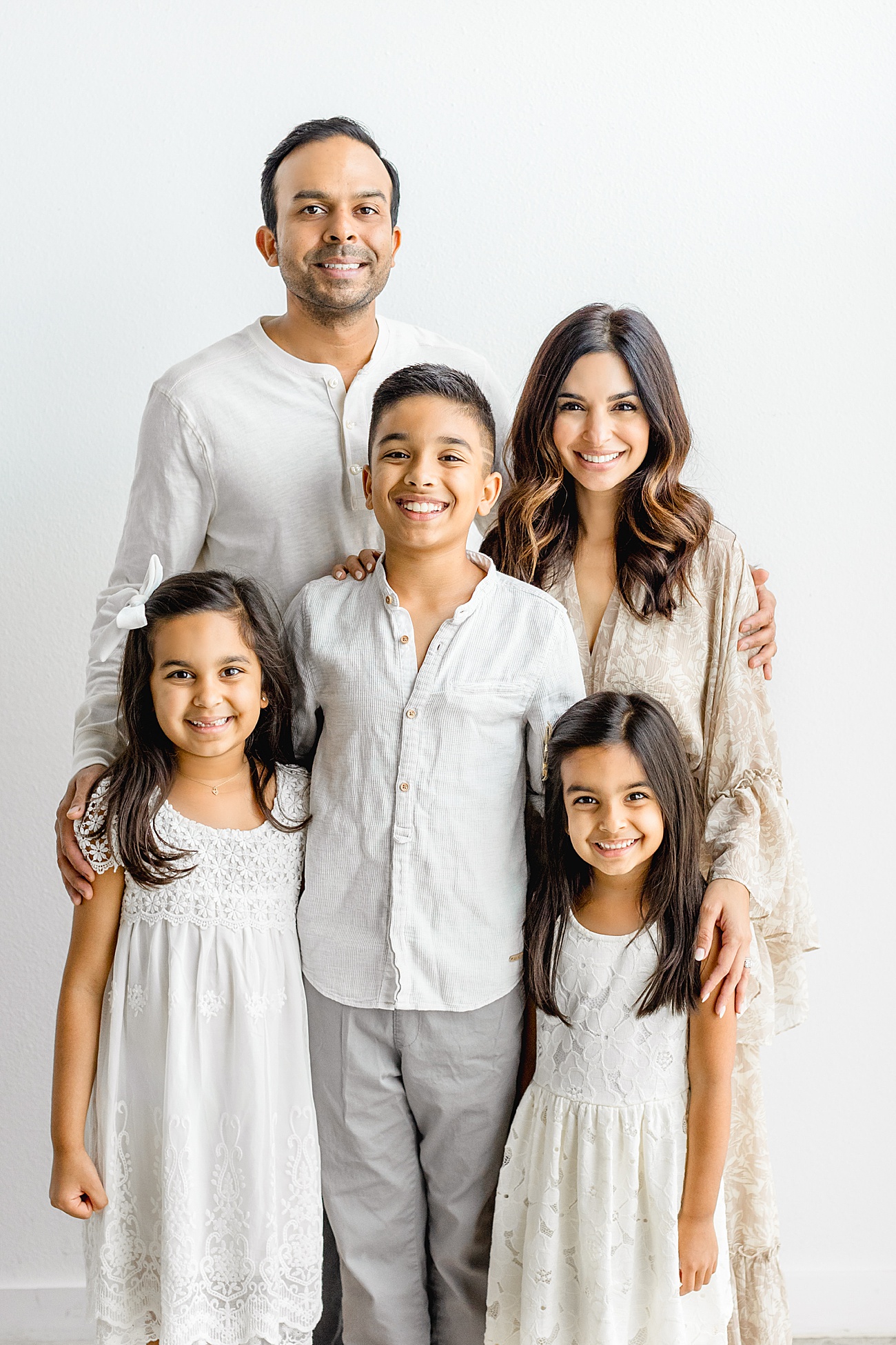 Family of five smiling at the camera wearing all neutrals during a family session in Austin with Sana Ahmed Photography.