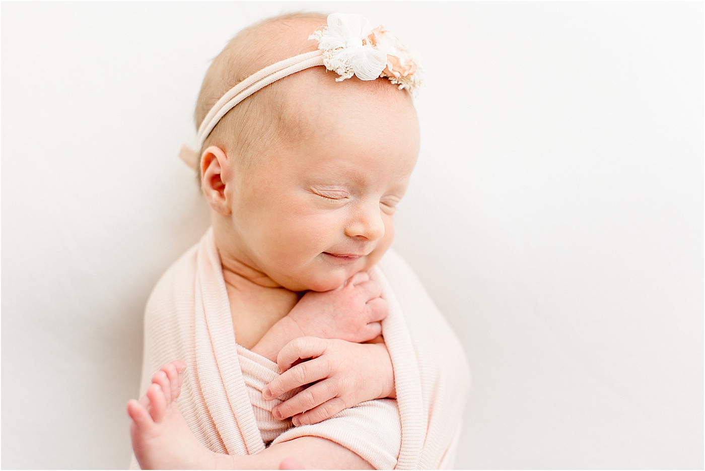 Image by Sana Ahmed Photography of baby girl in blush wrap sleeping during newborn session in Austin, Texas.