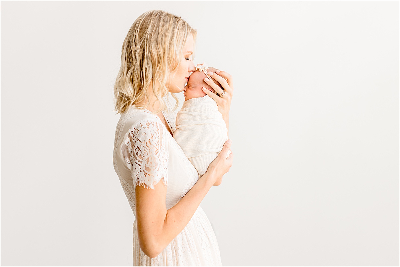 Mom holding baby girl and kissing her during newborn photos with Sana Ahmed Photography.
