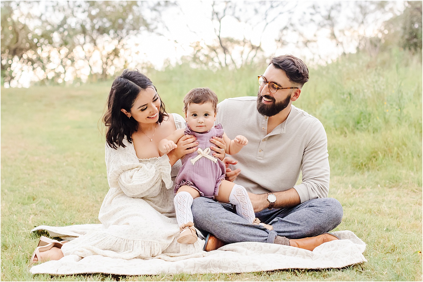 Mom and Dad sitting with daughter and smiling at her during Fall family session with Sana Ahmed Photography.