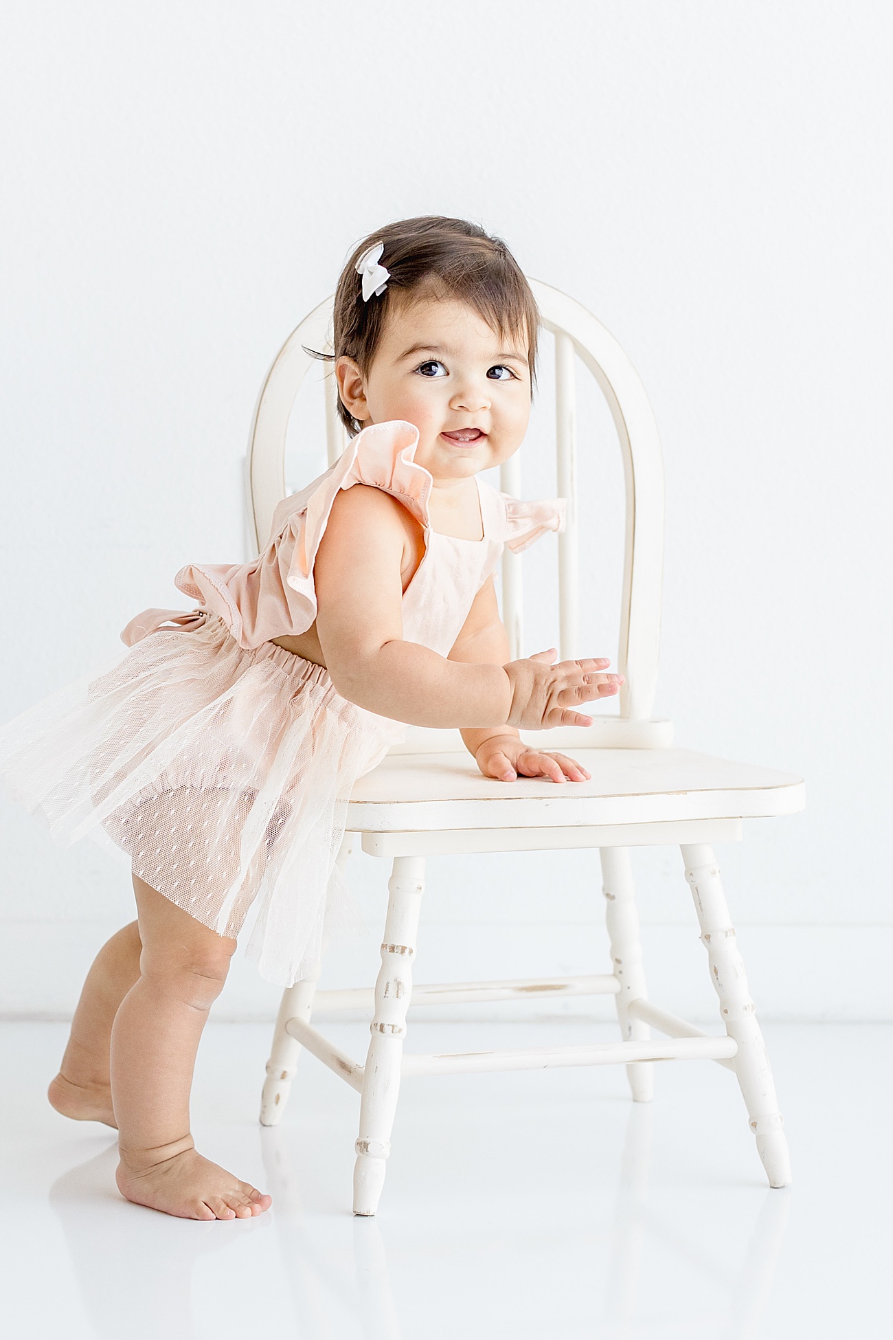 One Year Milestone Portraits with baby standing next to chair. Photo by Sana Ahmed Photography