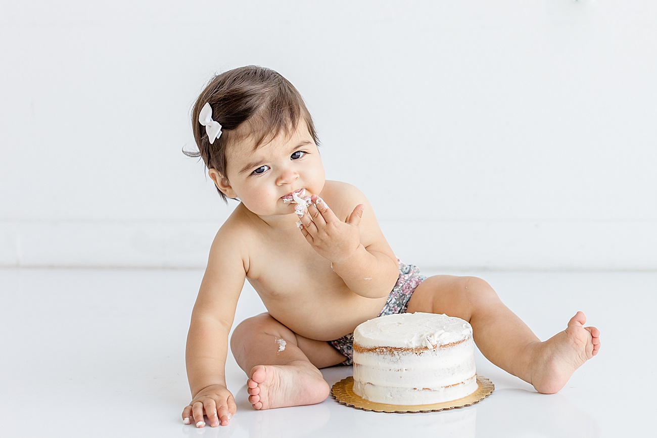 Baby testing frosting and making face during cake smash photos in Austin, TX studio. Photo by Sana Ahmed Photography