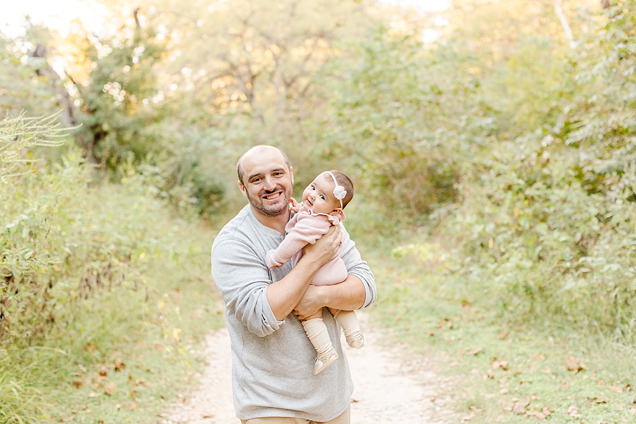 Dad holding baby girl as they smile at the camera during family session with Round Rock TX photographer, Sana Ahmed Photography
