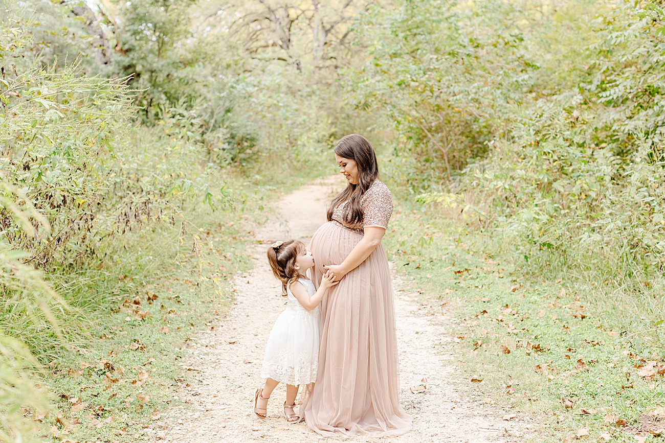 Little girl kissing Mom's baby bump during maternity session with Sana Ahmed Photography