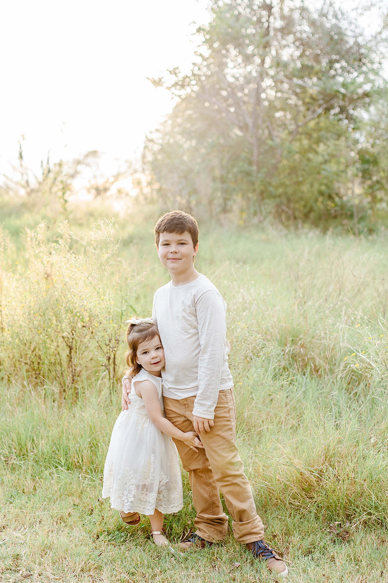 Sweet sibling portrait of brother and sister in sunny Austin, TX field. Photo by Sana Ahmed Photography