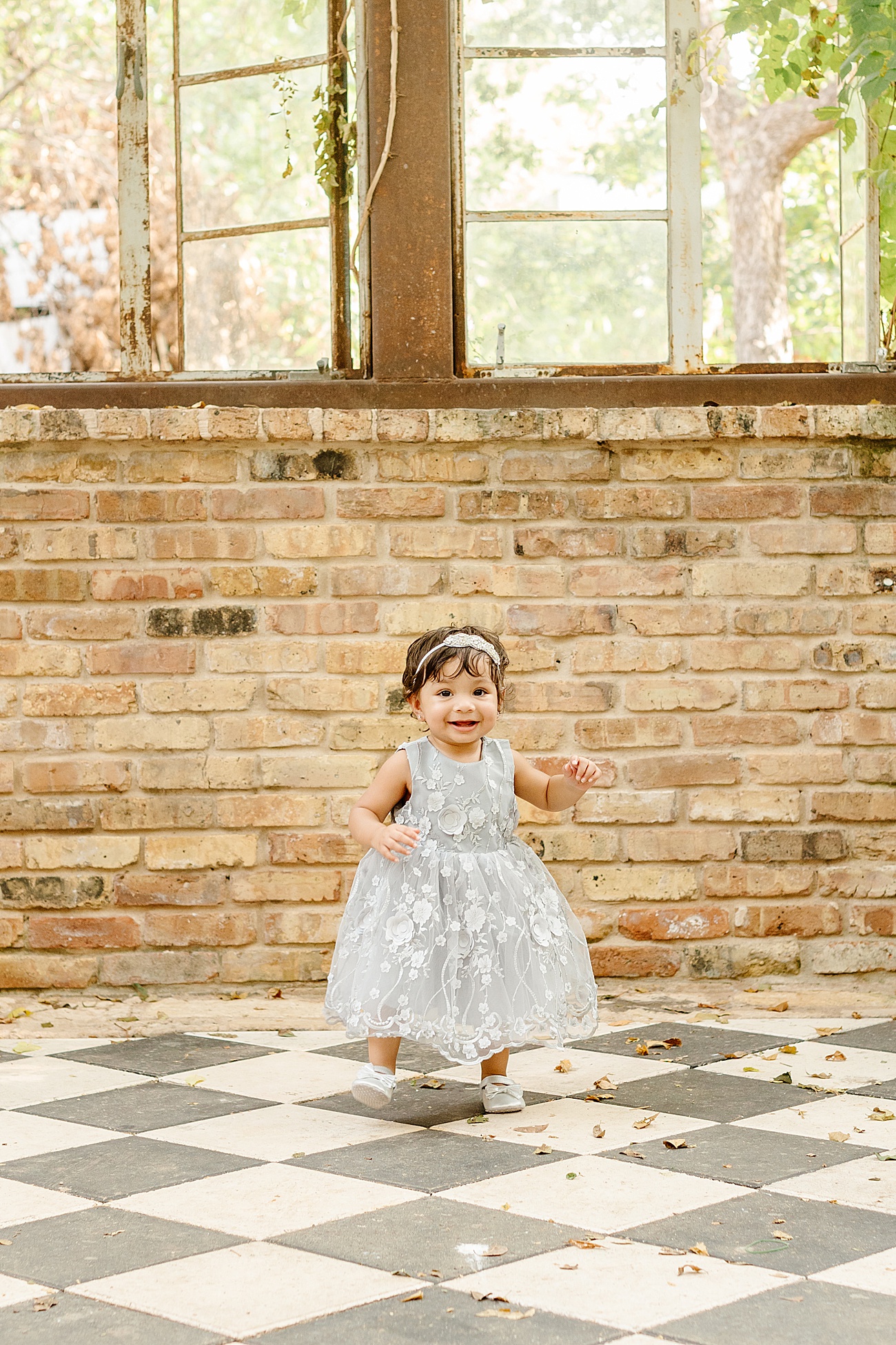 Little girl smiling inside vintage greenhouse in Austin, TX. Photo by Sana Ahmed Photography
