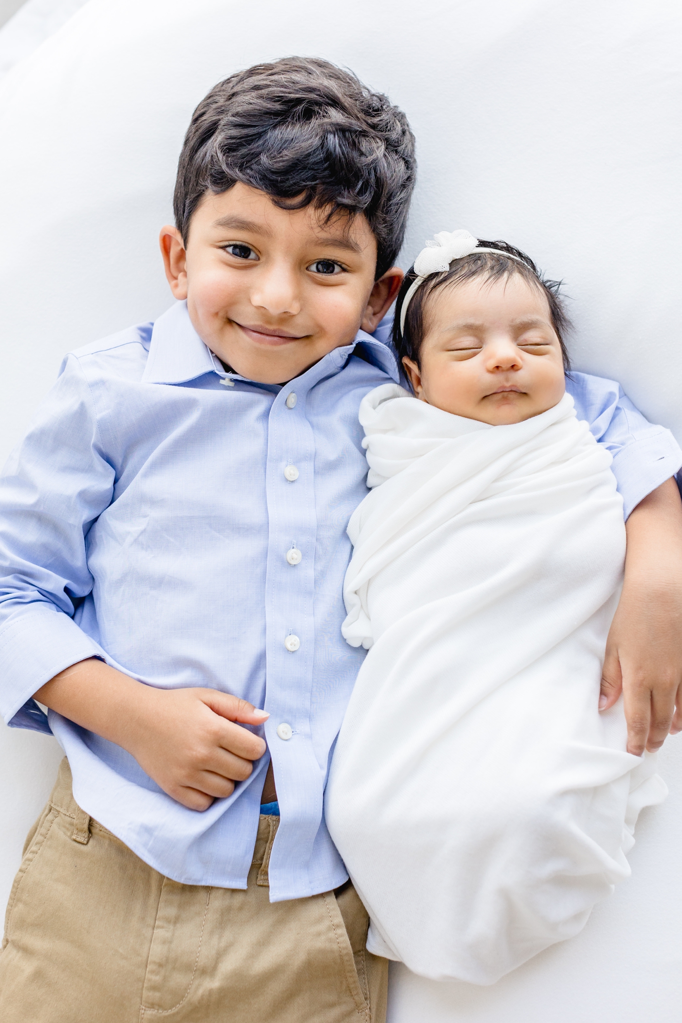 Brother holding baby sister in arms. Photo by Sana Ahmed Photography.