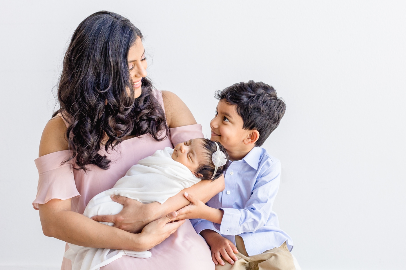 Mom smiling at oldest child during newborn session with video. Photo by Sana Ahmed Photography.