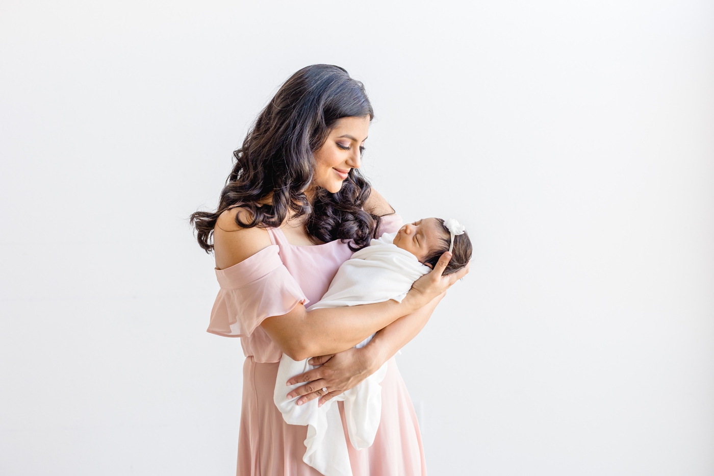 Beautiful Mom holding newborn baby in light and airy Austin studio. Photo by Sana Ahmed Photography.