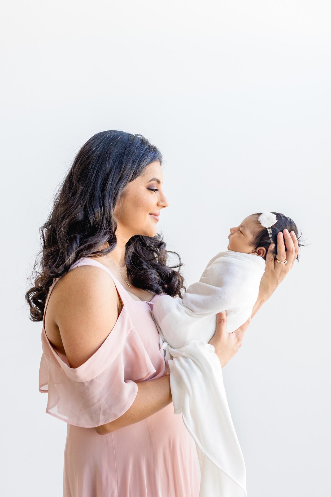 Mom looking at baby girl during newborn session with Sana Ahmed Photography.