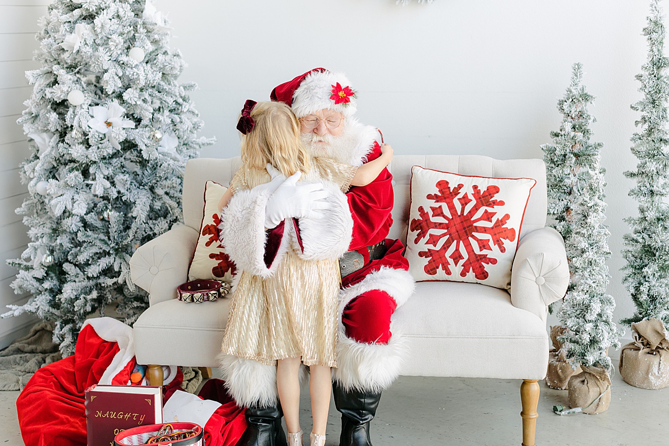 Little girl in gold dress hugging Santa. Photo by Austin, TX photographer, Sana Ahmed Photography.