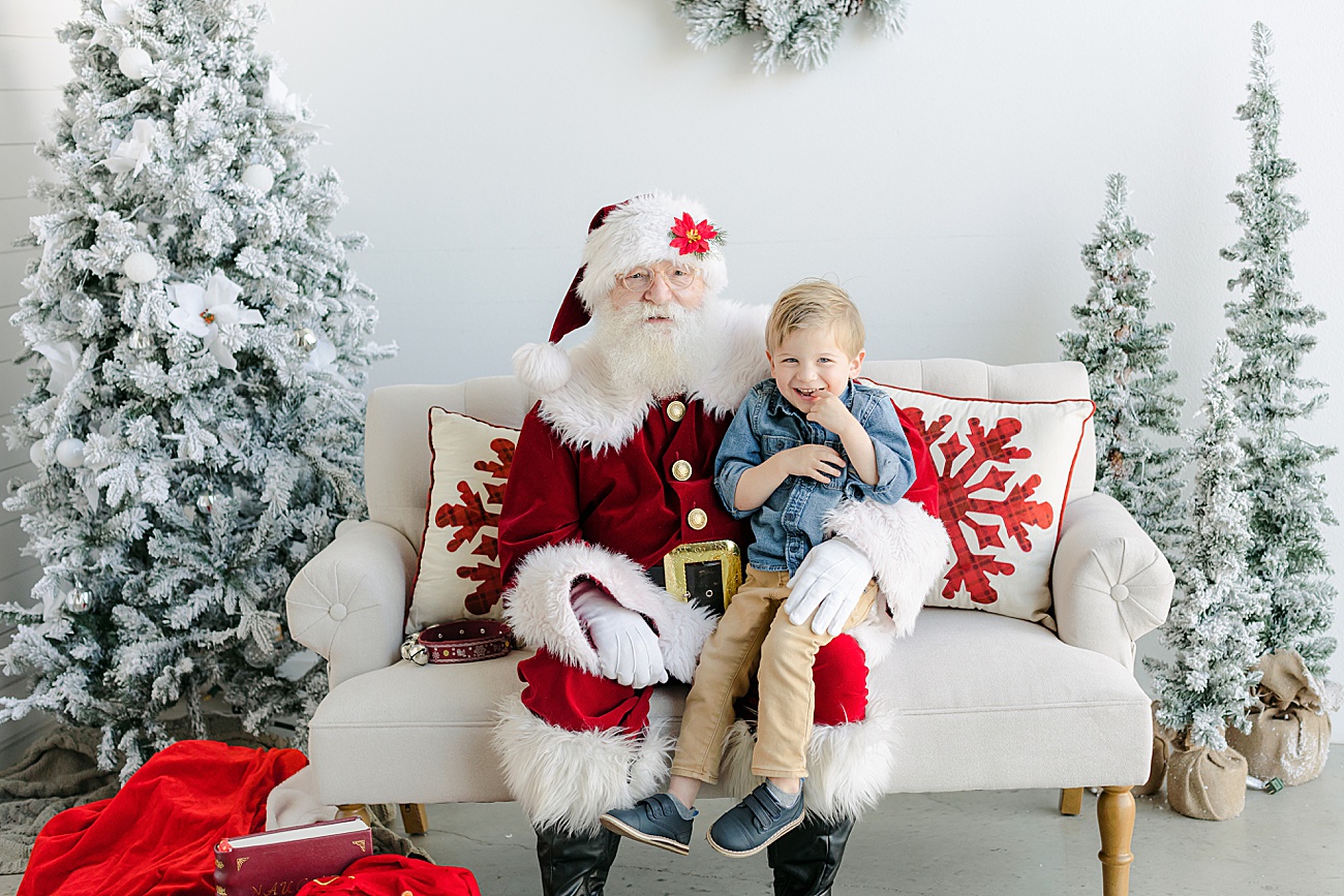 Smiling toddler sitting on Santa's lap. Photo by Sana Ahmed Photography.