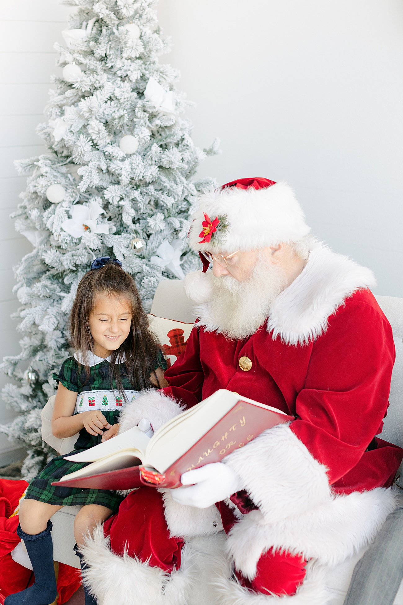 Little girl in smocked dress looking at Santa's list. Photo by Sana Ahmed Photography.