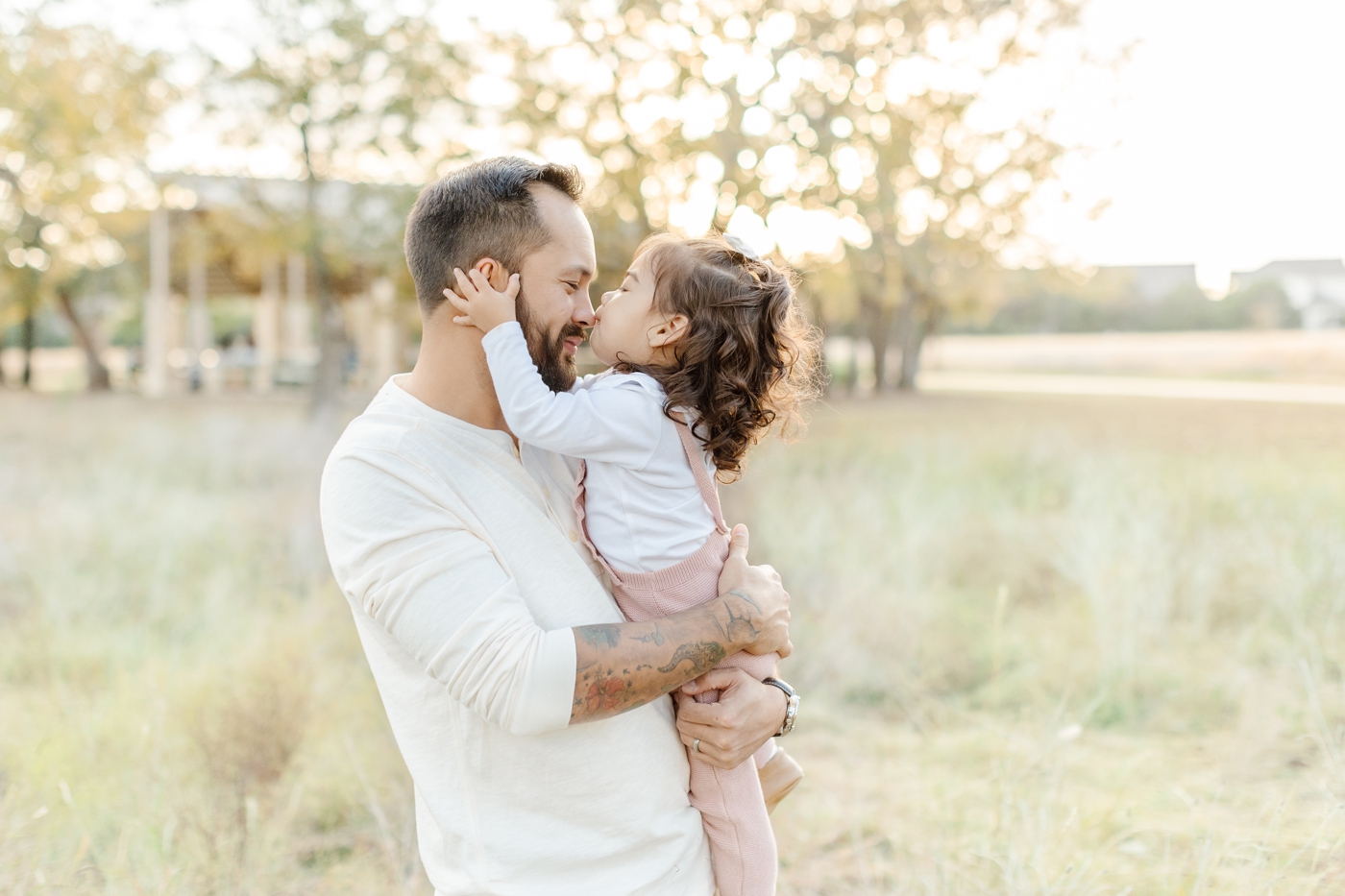 Little girl kisses Dad on nose during sweet moment in Austin, TX family portrait session. Photo by Sana Ahmed Photography.