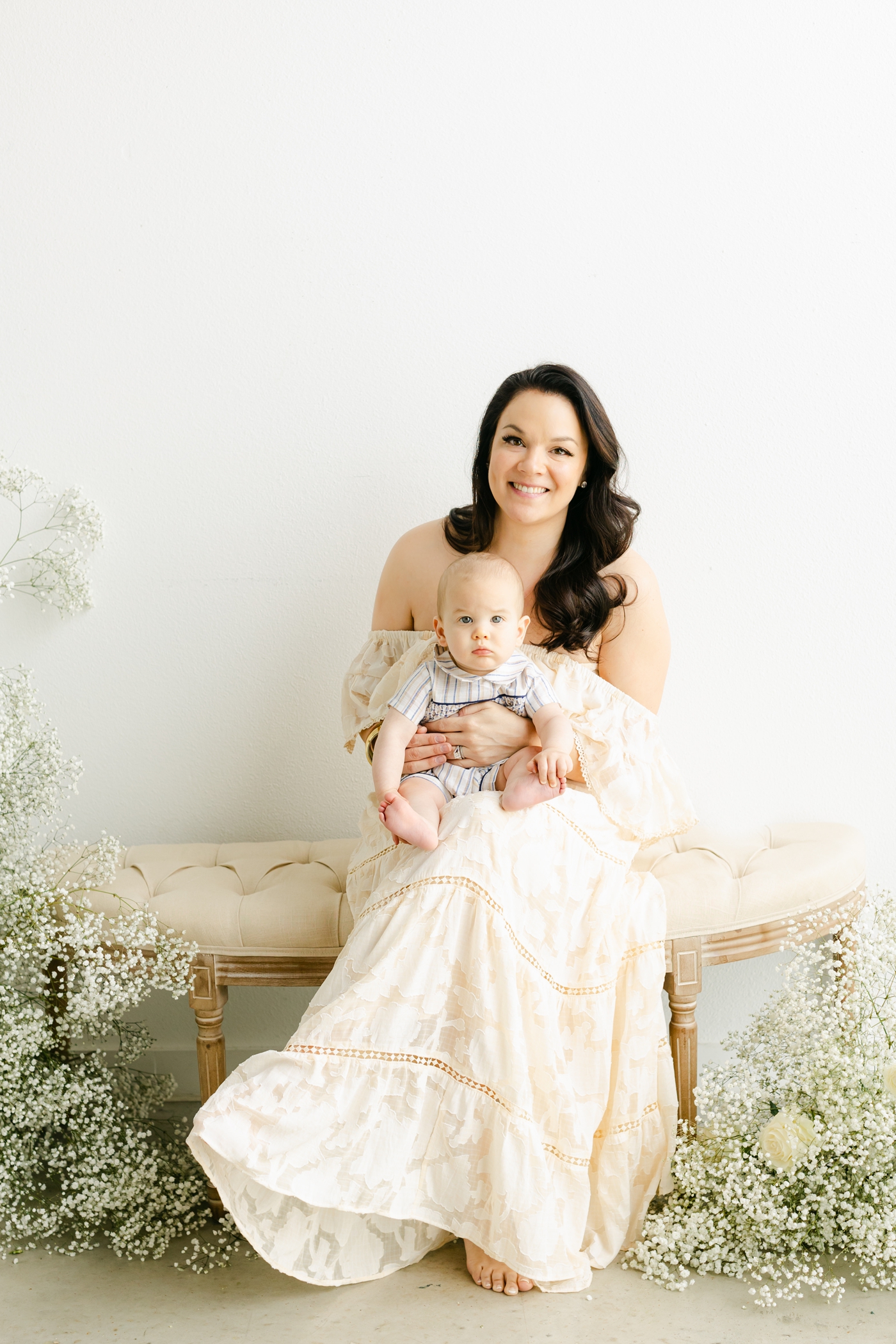 Mom in off-white maxi dress sitting on bench with baby. Photo by Sana Ahmed Photography.