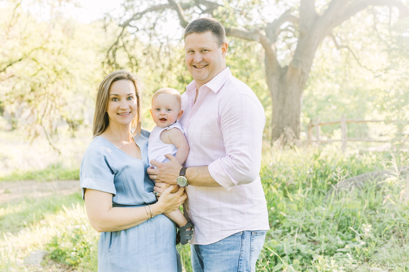 Family of three smiling at the camera during photoshoot in Austin, TX. Photo by Sana Ahmed Photography.