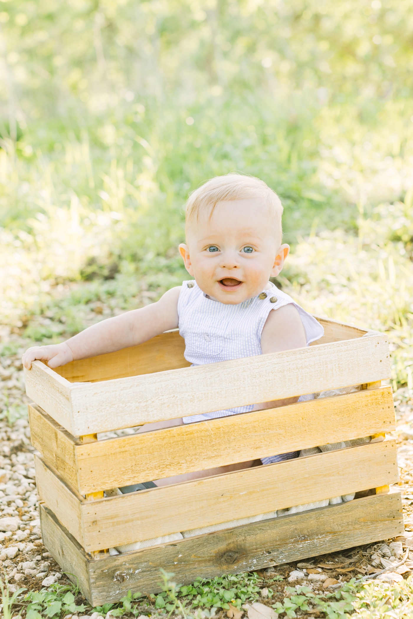 Baby sitting in wooden crate during 6 month milestone session. Photo by Sana Ahmed Photography.