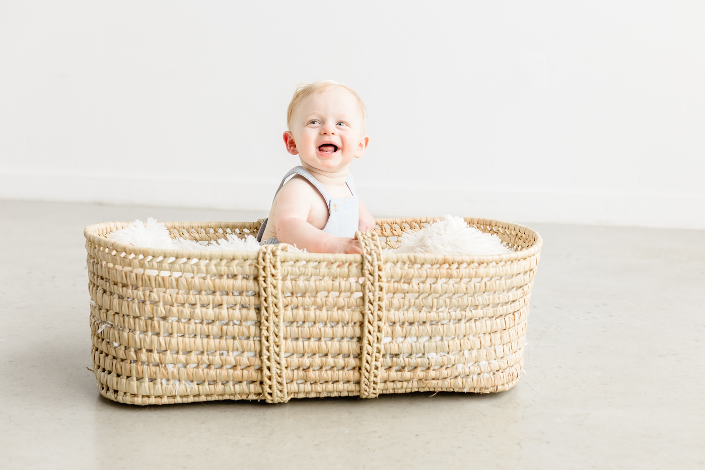 First birthday session with happy baby as he sits in moses basket. Photo by Sana Ahmed Photography.