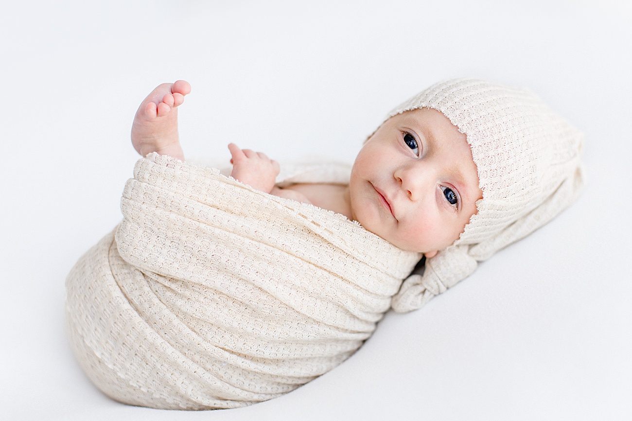 Baby in oatmeal swaddle looking at camera during newborn session with Sana Ahmed Photography.