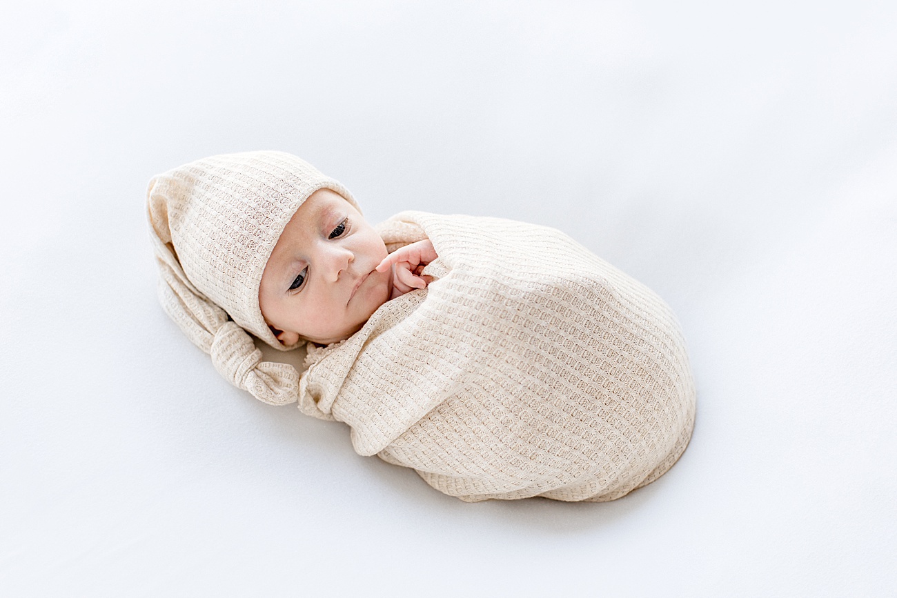 Baby boy in oatmeal swaddle and knotted hat. Photo by Sana Ahmed Photography.