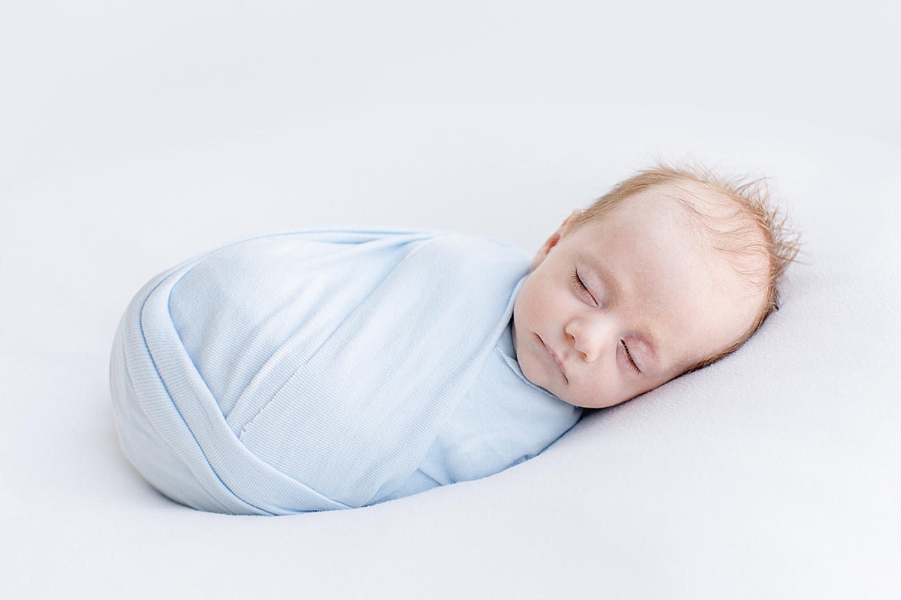 Baby in blue knit swaddle sleeping during newborn photoshoot with Austin photographer, Sana Ahmed Photography.