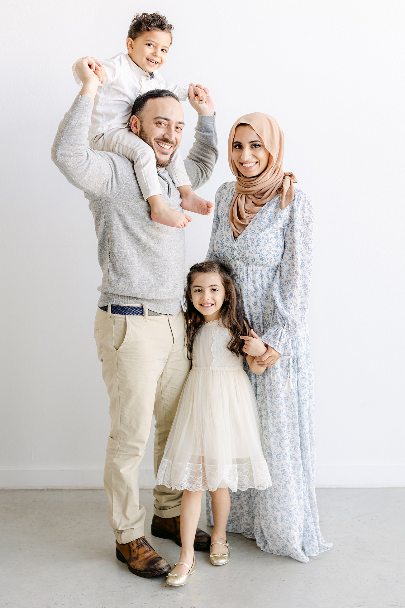Family of four smiling at camera in light and airy portrait by Sana Ahmed Photography.
