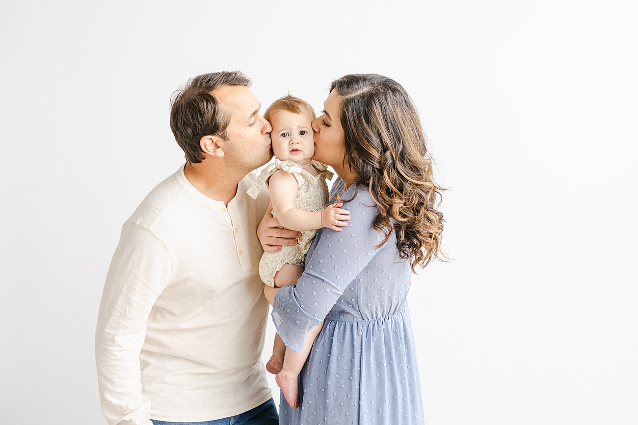 Mom and Dad kissing baby's face during family photos in Austin, TX. Photo by Sana Ahmed Photography.