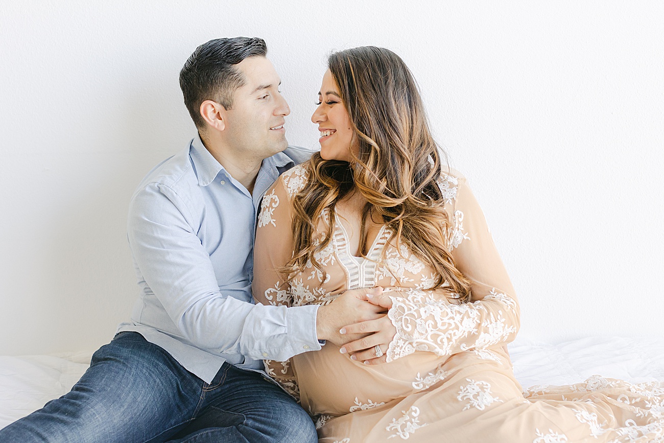 Sweet candid of expecting first time parents smiling at each other. Photo by Sana Ahmed Photography.