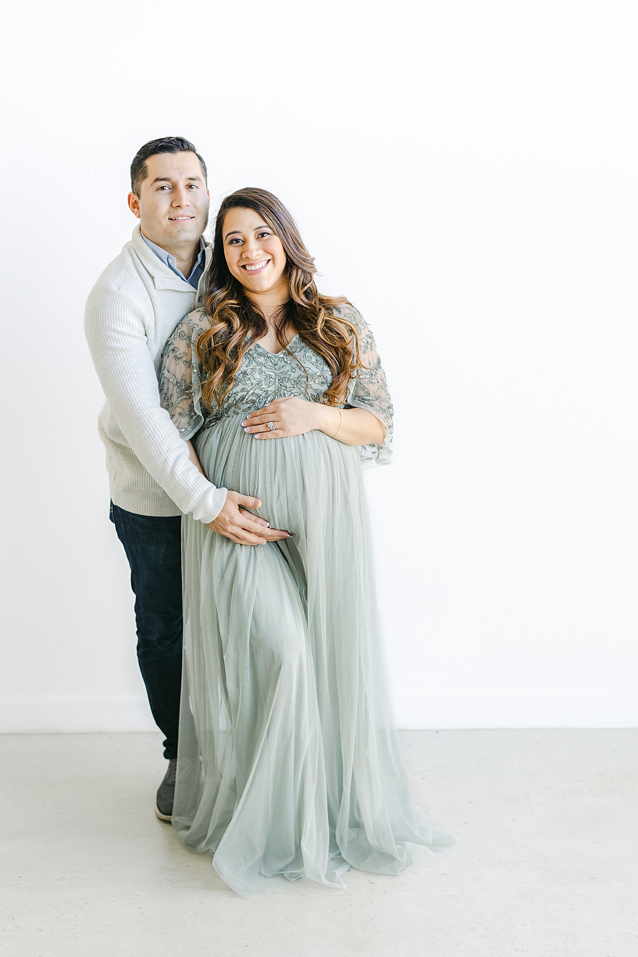 Sweet photo of expecting parents smiling at the camera during maternity photos with Sana Ahmed Photography.