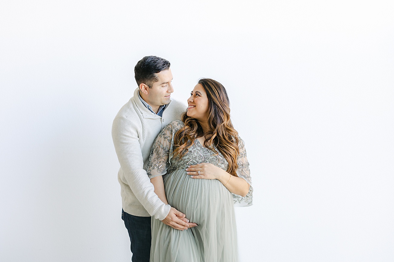 Mom looking up at Dad as she hugs her baby bump during maternity portraits with Sana Ahmed Photography.