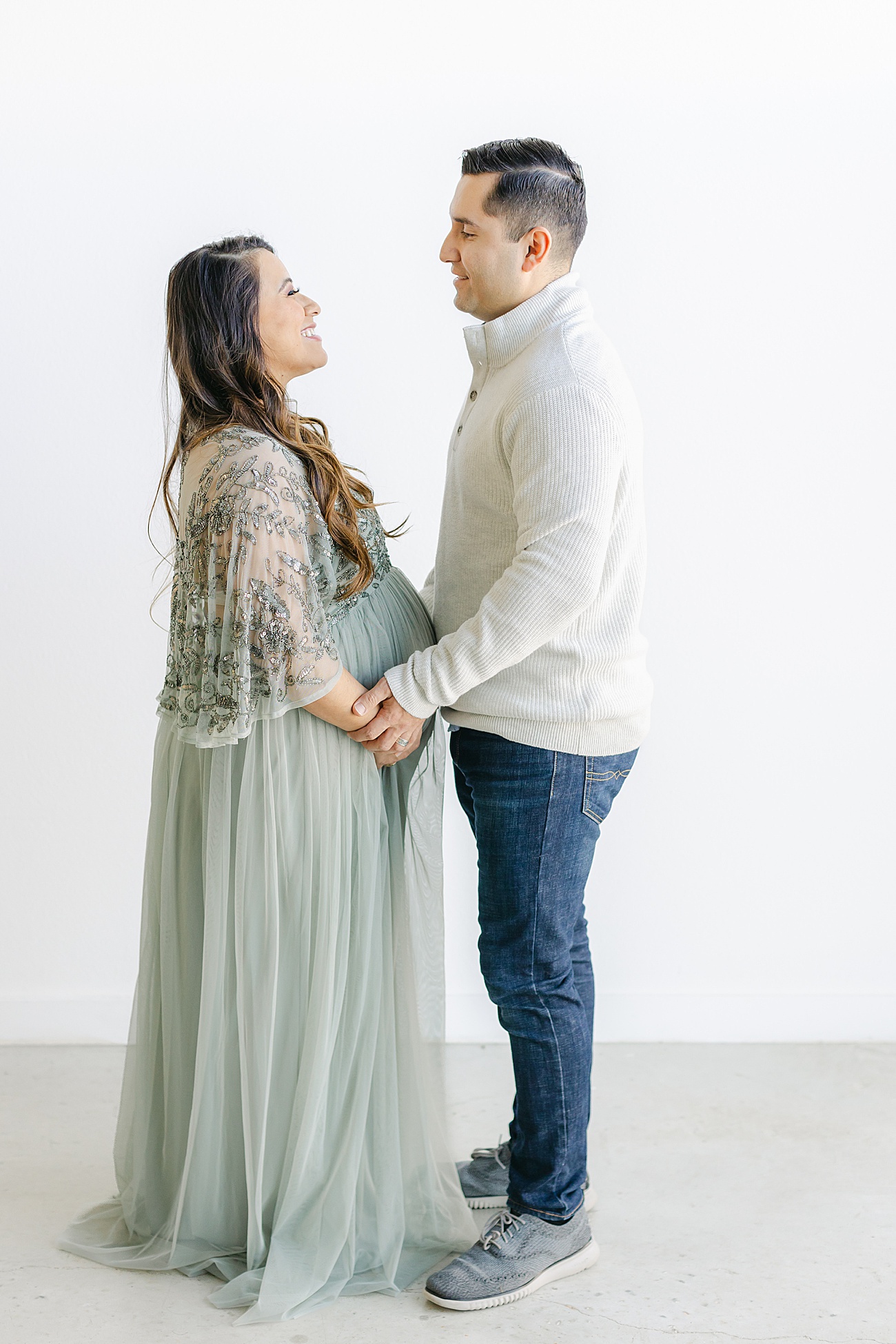Mom and Dad looking at each other in studio maternity session for first baby. Photo by Sana Ahmed Photography.