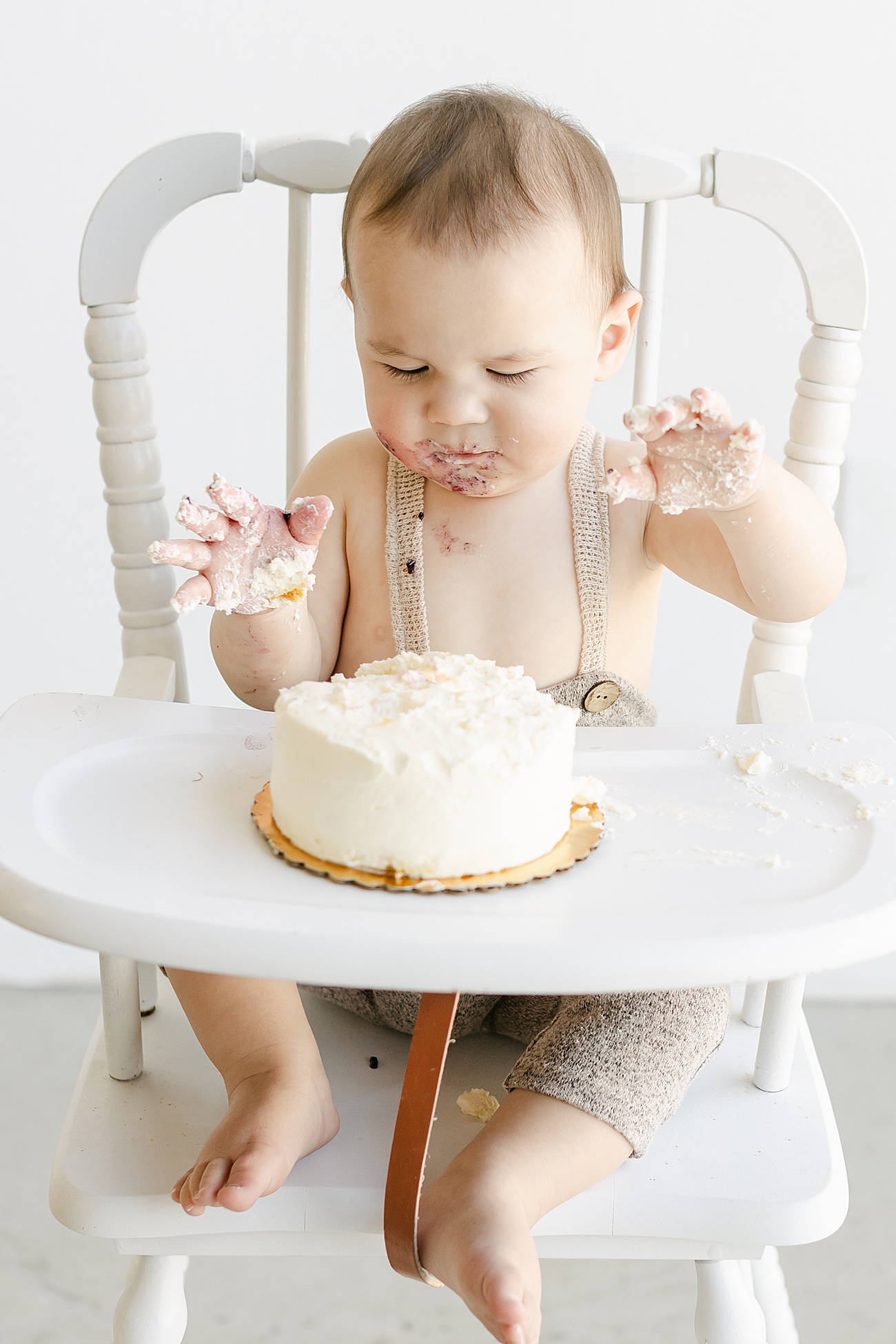 Little boy beginning to dig into cake smash during first birthday photos with Austin Texas photographer, Sana Ahmed Photography.
